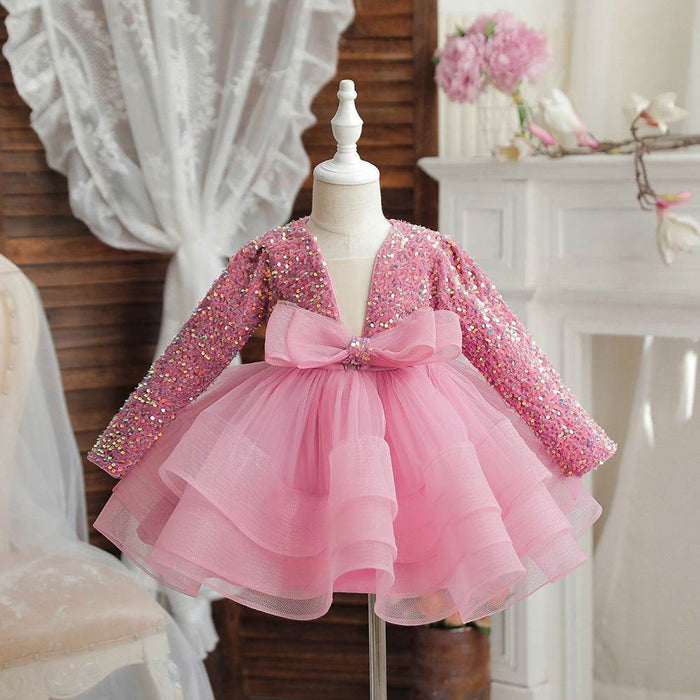 Pink sequin dress with a bow on a mannequin against a decorative background