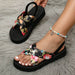 Black floral sandals being worn on a gray textured surface