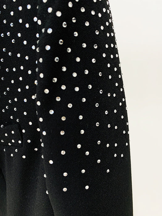 Black dress with white polka dot pattern on a beige background