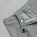 Close-up of gray pants with button details on a gray background