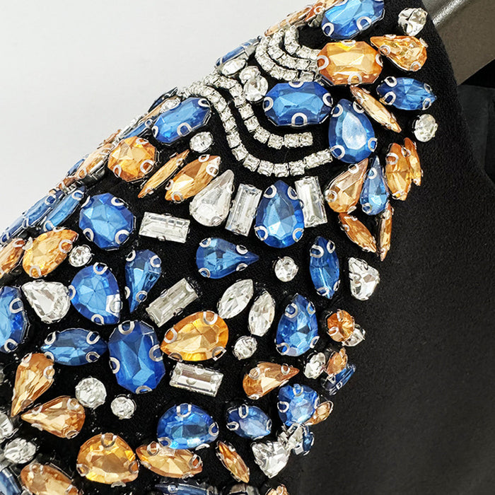 Close-up of a decorative item with blue, orange, and silver gemstones on a black background