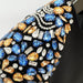 Close-up of a decorative item with blue, orange, and silver gemstones on a black background