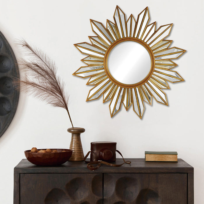 Decorative sunburst mirror on a wall above a wooden cabinet with decorative items.