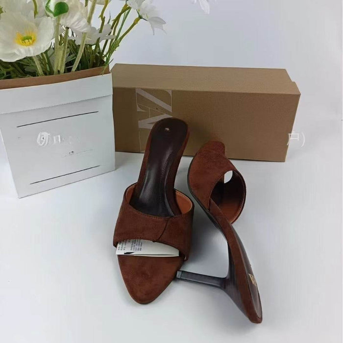 Brown suede mules with a box and flowers on a white background