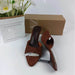 Brown suede mules with a box and flowers on a white background