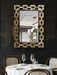 Decorative mirror with geometric frame above a set dining table in a restaurant.