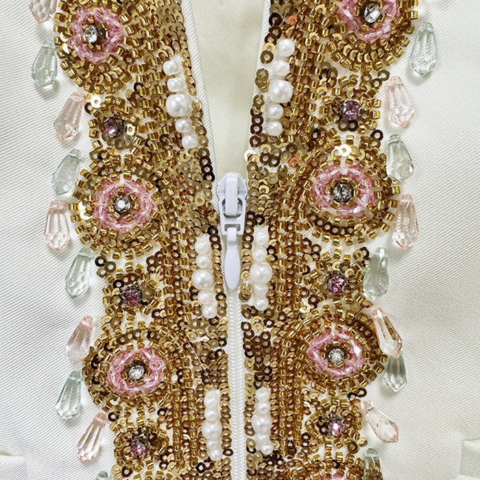 Close-up of a decorative fabric strip with gold, pink, and white beads on a light background