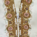 Close-up of a decorative fabric strip with gold, pink, and white beads on a light background