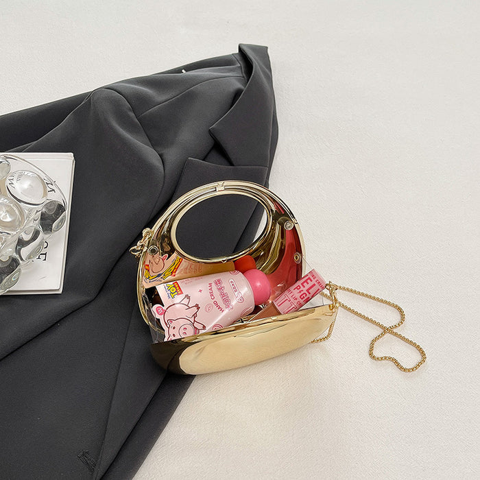 Small gold handbag with cosmetic items on a light gray surface