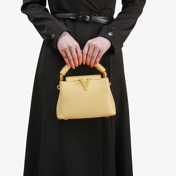 Person holding a gold handbag with a plain background
