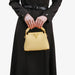 Person holding a gold handbag with a plain background