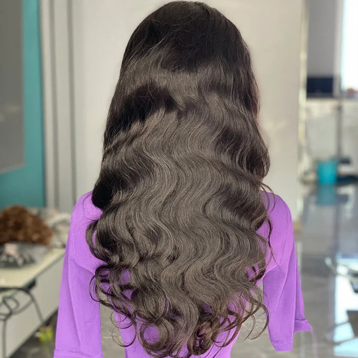 Person with long, wavy hair styled in a ponytail, wearing a purple shirt in an indoor setting.