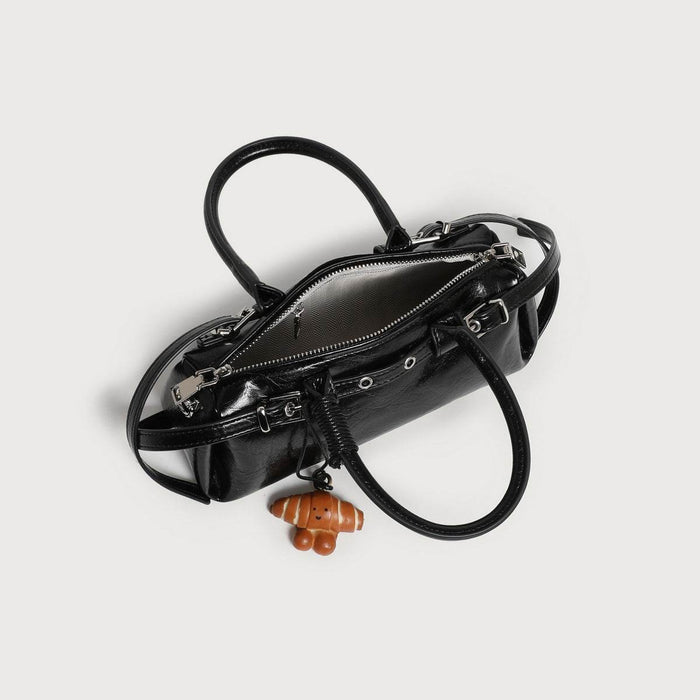 Black handbag with a small brown dog-shaped charm on a light gray background