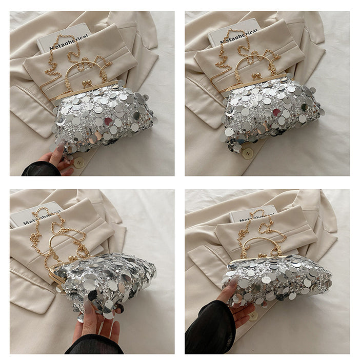 Silver sequin clutch bag with gold handle held by a person on a light background