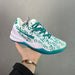 White and teal sneaker with unique design held by a hand against a gray background