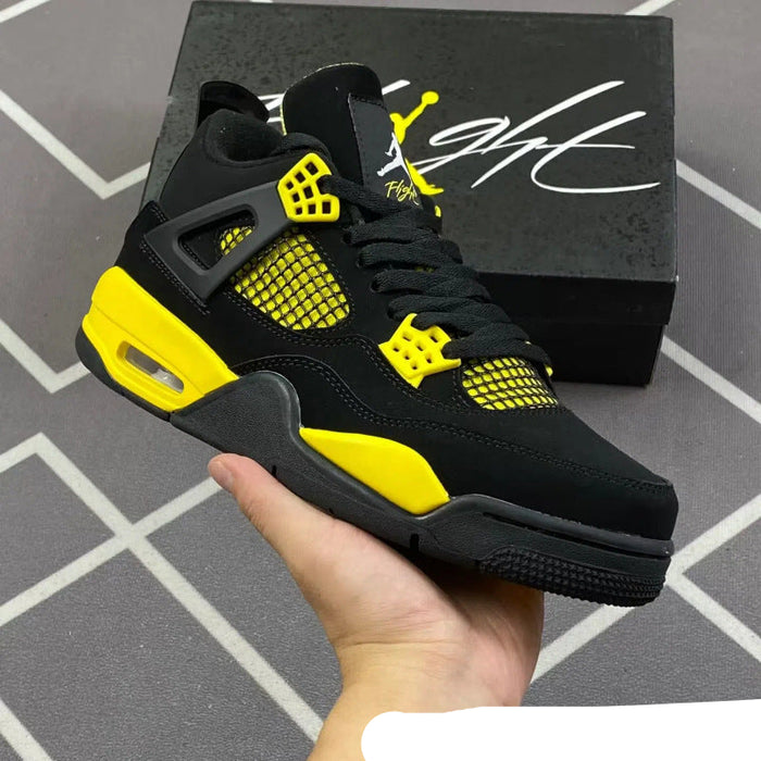 Black and yellow sneaker held by a hand with a black box featuring a logo in the background.