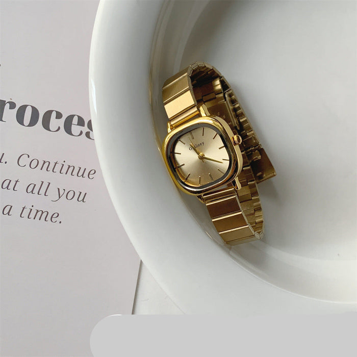 Gold watch on a white dish with text in the background