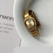 Gold watch on a white dish with text in the background