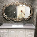 Decorative mirror with ornate frame above a sink in a bathroom setting.