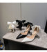Black and white high-heeled shoes with decorative bows on a gray surface.