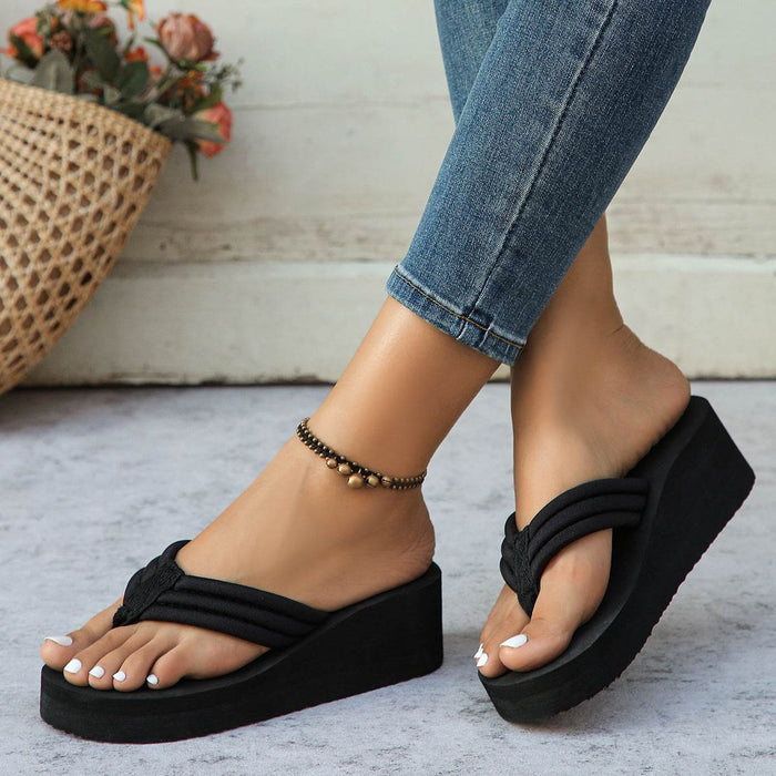 Black platform sandals worn with blue jeans on a light background