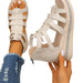 Beige strappy sandals worn with ripped jeans on a white background