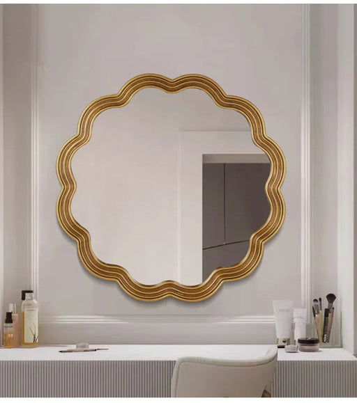 Decorative gold-framed mirror on a wall with grooming products below.