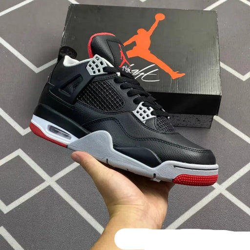 Black and red sneaker held in hand with Jordan box in the background