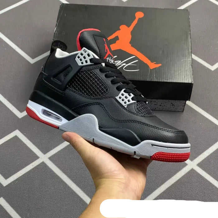 Black and red sneaker held in hand with Jordan box in the background