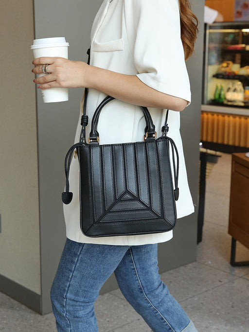 Person holding a black handbag and a coffee cup in an indoor setting