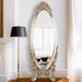 Decorative oval mirror with ornate frame in a room setting