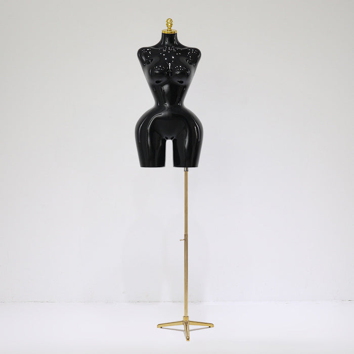 Black mannequin torso on a gold stand against a white background