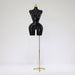 Black mannequin torso on a gold stand against a white background