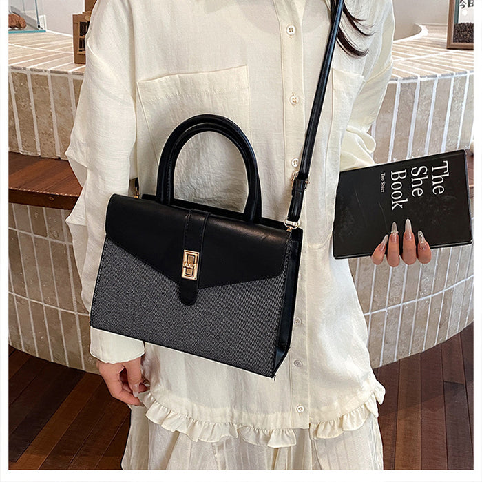 A woman in a white ruffled blouse carries a structured handbag with a black top handle and flap, featuring a textured dark gray lower body and a gold-tone front clasp. She is holding a black book in a tiled indoor setting.