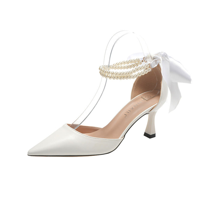 White high-heeled shoe with pearl ankle strap and bow on a white background