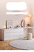 Modern white dresser with mirror and decor items in a room setting.