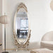 Decorative oval mirror with intricate design in a room setting.
