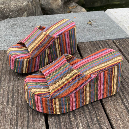 Colorful striped sandals on a wooden surface with a natural background