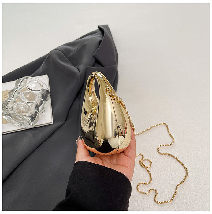 Gold evening bag held by a hand with a gray fabric background