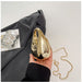 Gold evening bag held by a hand with a gray fabric background
