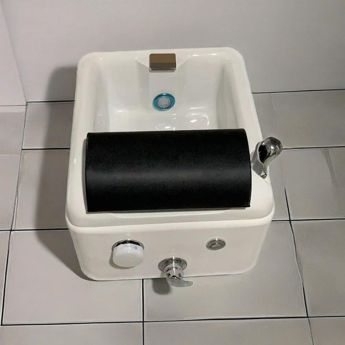 White ceramic sink with black soap holder on a tiled floor