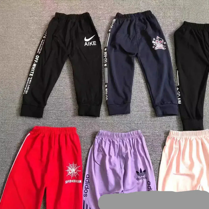 Collection of various pants with different brands on a gray surface