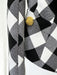 Close-up of a black and white checkered fabric with a gold button on a white background