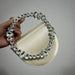 Handbag with a decorative crystal handle held by a hand against a gray background