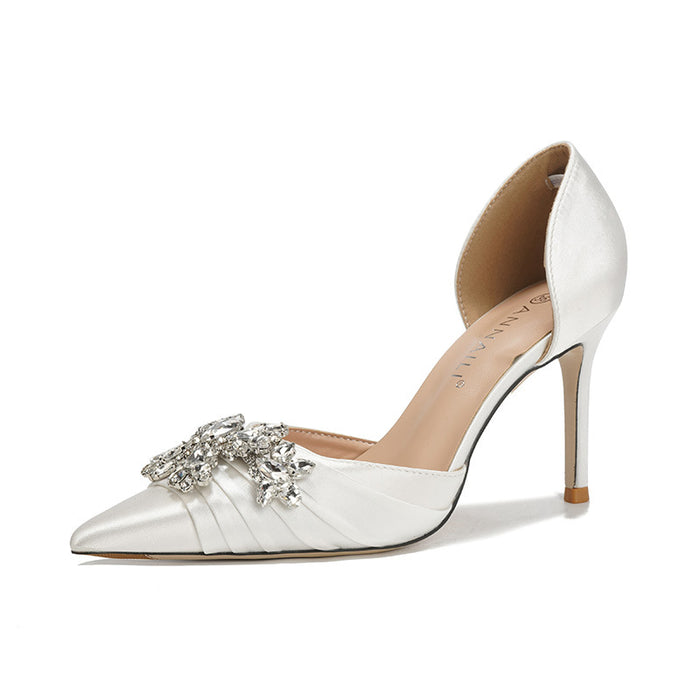 White high-heeled shoe with a decorative brooch on a white background