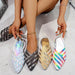 Four colorful shoes held by a person on a light gray floor.
