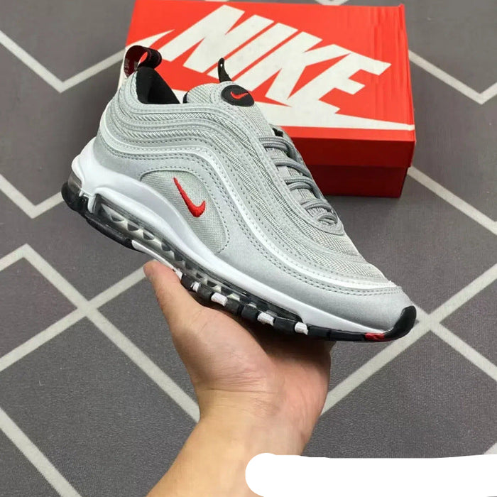 Gray sneaker with red Nike logo held by a hand, with a red Nike box in the background.