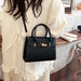 A black crocodile-embossed handbag with gold-tone hardware, worn crossbody by a person in a cream-colored ruffled blouse in a cafe setting.