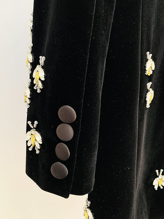 Black blazer with floral embroidery and buttons on a light background