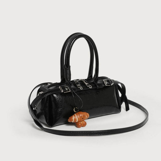 Black handbag with a small brown dog toy on a light gray background